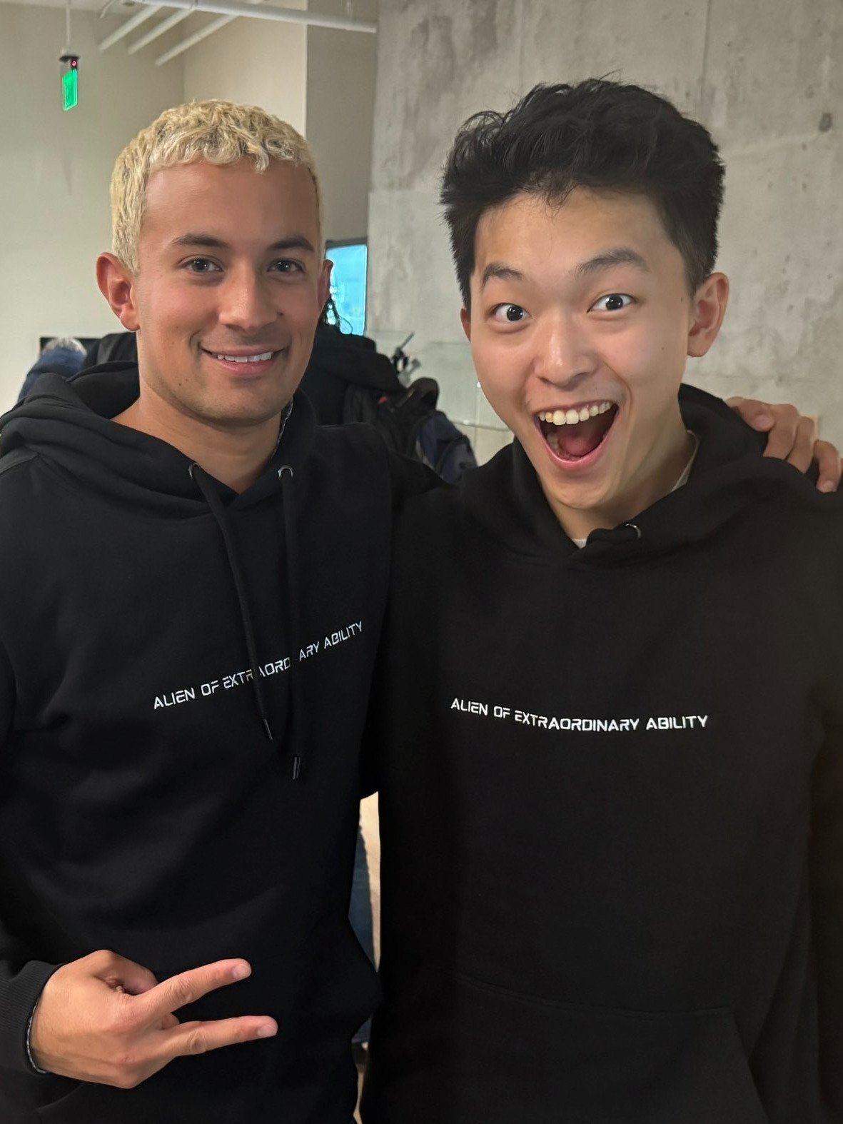 Two people wearing black Alien of Extraordinary Ability hoodies
